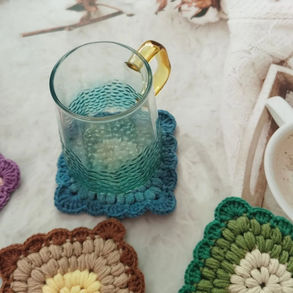 Crocheted grandmother lattice insulated cup placemat in wool, shown in one of four colours