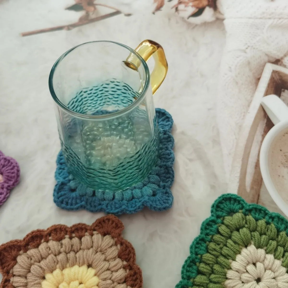 Crocheted grandmother lattice insulated cup placemat in wool, shown in one of four colours