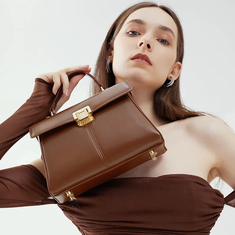 Black leather women's shoulder bag with clasp closure showing internal zippered compartment and adjustable strap