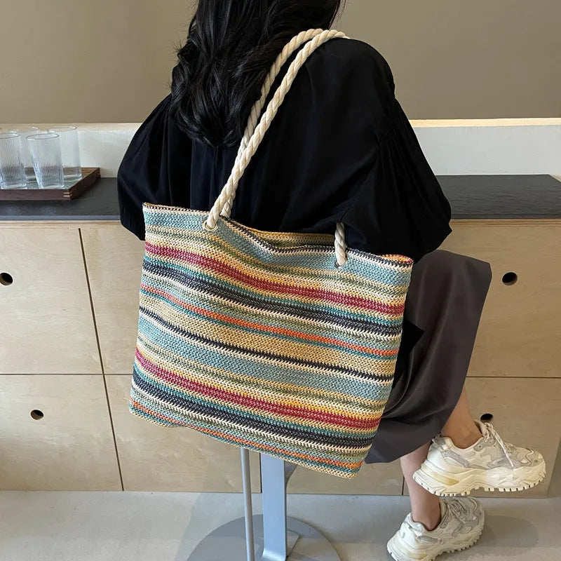 Blue straw woven large capacity shoulder bag with adjustable strap on a neutral background