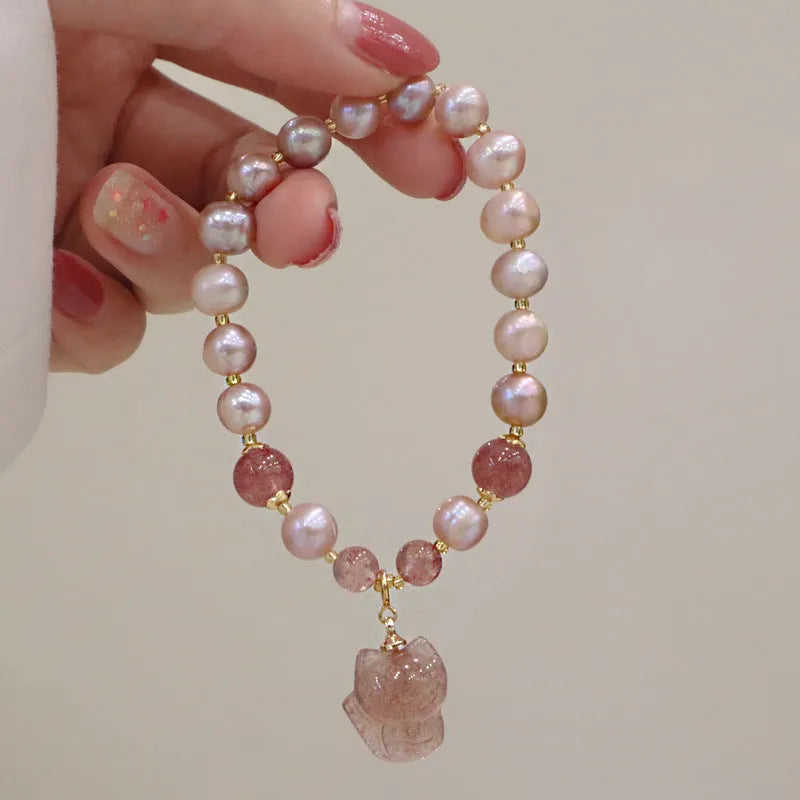 Light pink freshwater pearl bracelet with a strawberry quartz fox charm on a metal chain.