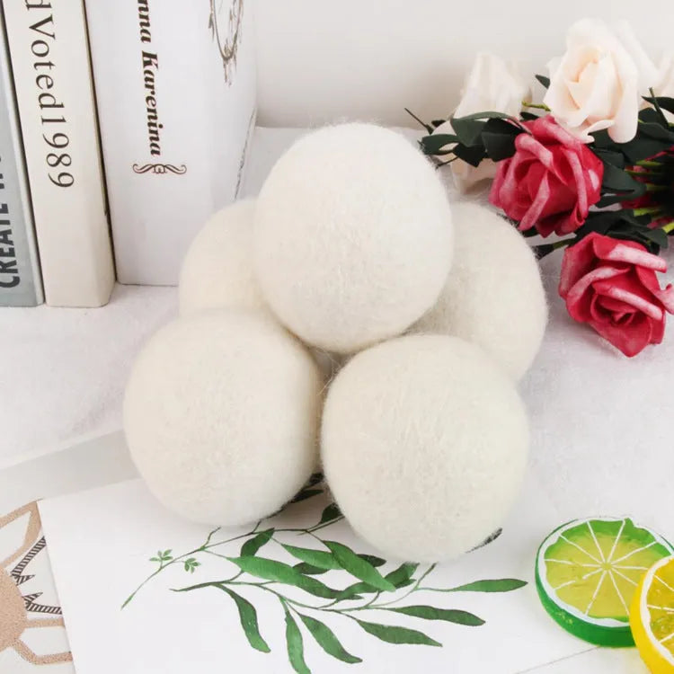 Set of 100% wool anti-static drying balls next to a plain cotton storage bag on a laundry background.