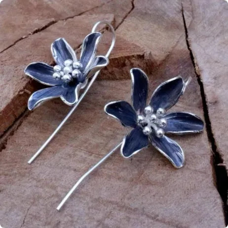 Purple flower-shaped alloy earrings with electroplated finish on white background