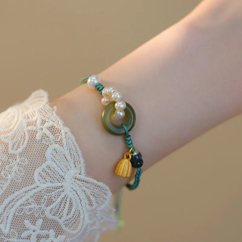 Close-up of a hand-woven flexible wire watch band with a pearl peace buckle closure.