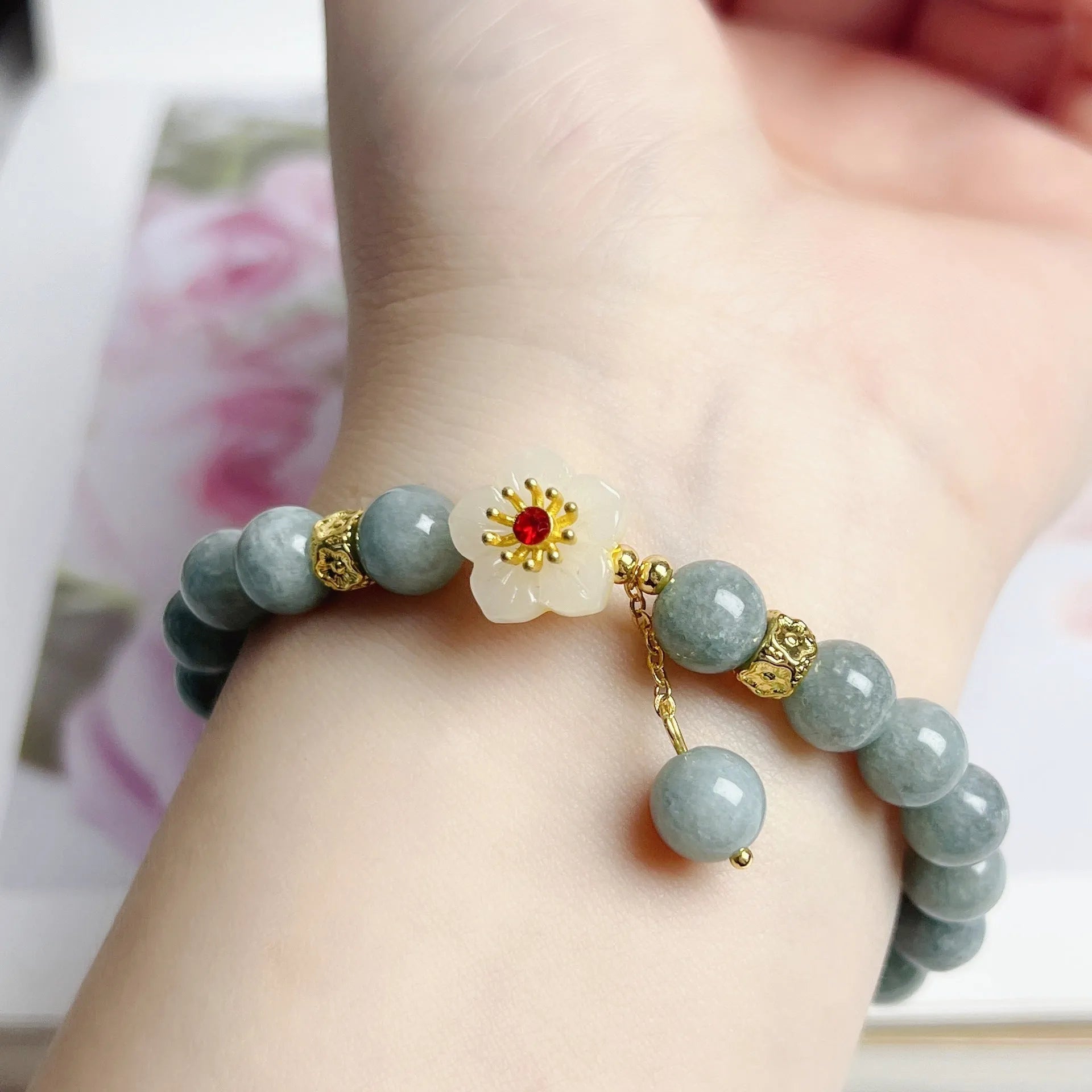 Handmade green jade bracelet with adjustable cotton cord fastening on a wrist.