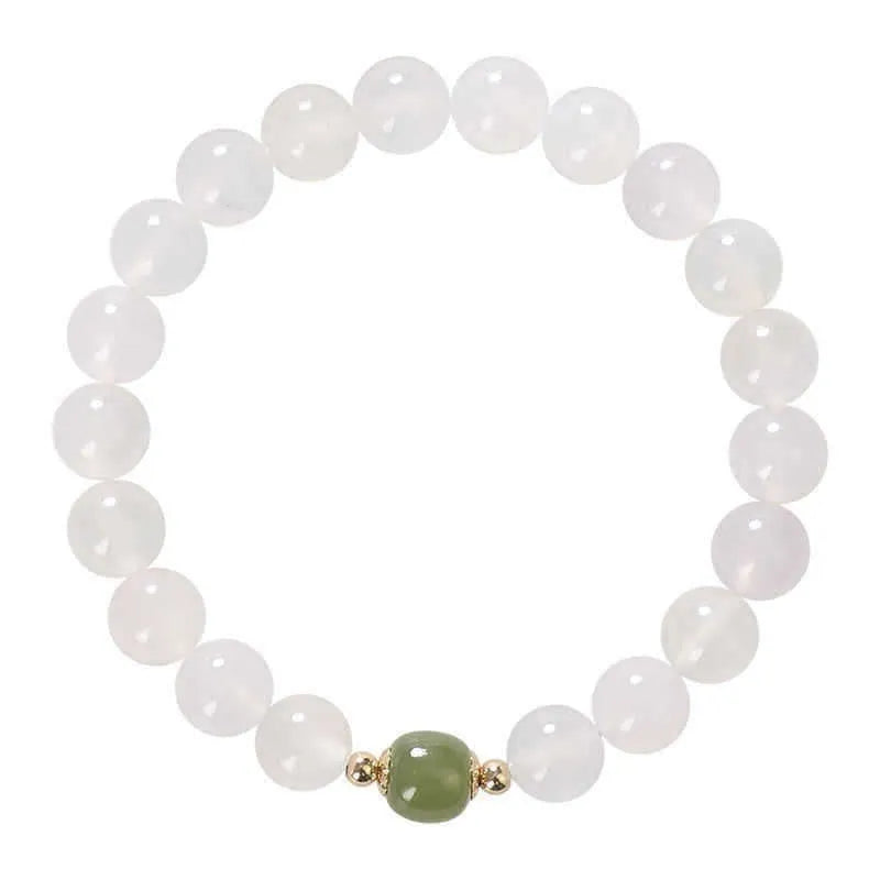 Handmade natural white agate and Hetian jade crystal bracelet with cinnabar inlay on a wrist.