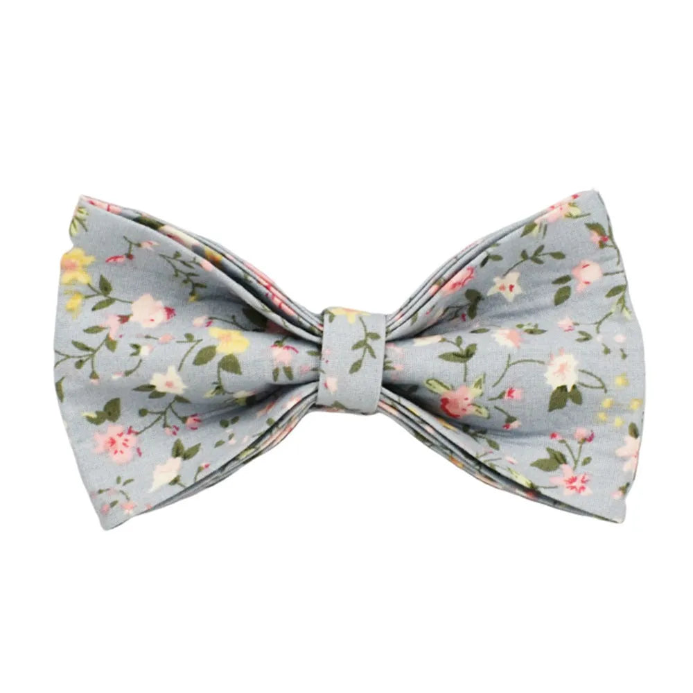 Blue floral pattern dog collar set with matching leash, vest, bow, and poop bag holder on wooden background