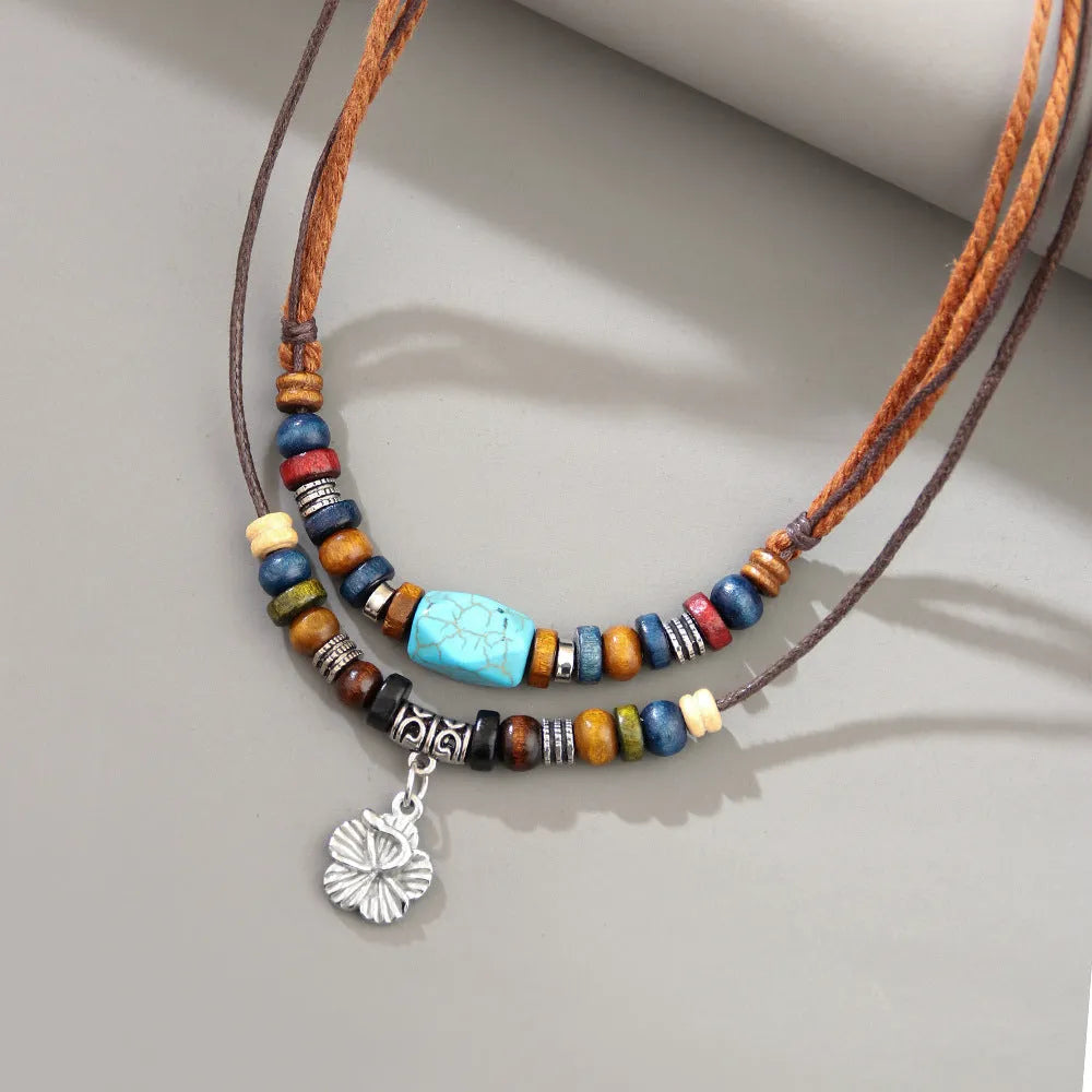 Turquoise wax rope necklace with geometric alloy pendant featuring floral engraving details
