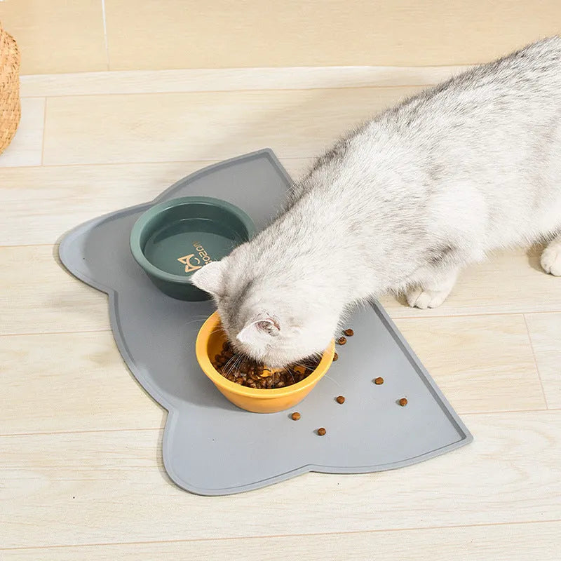 Blue cat head shaped silicone pet feeding mat placed under food and water bowls.