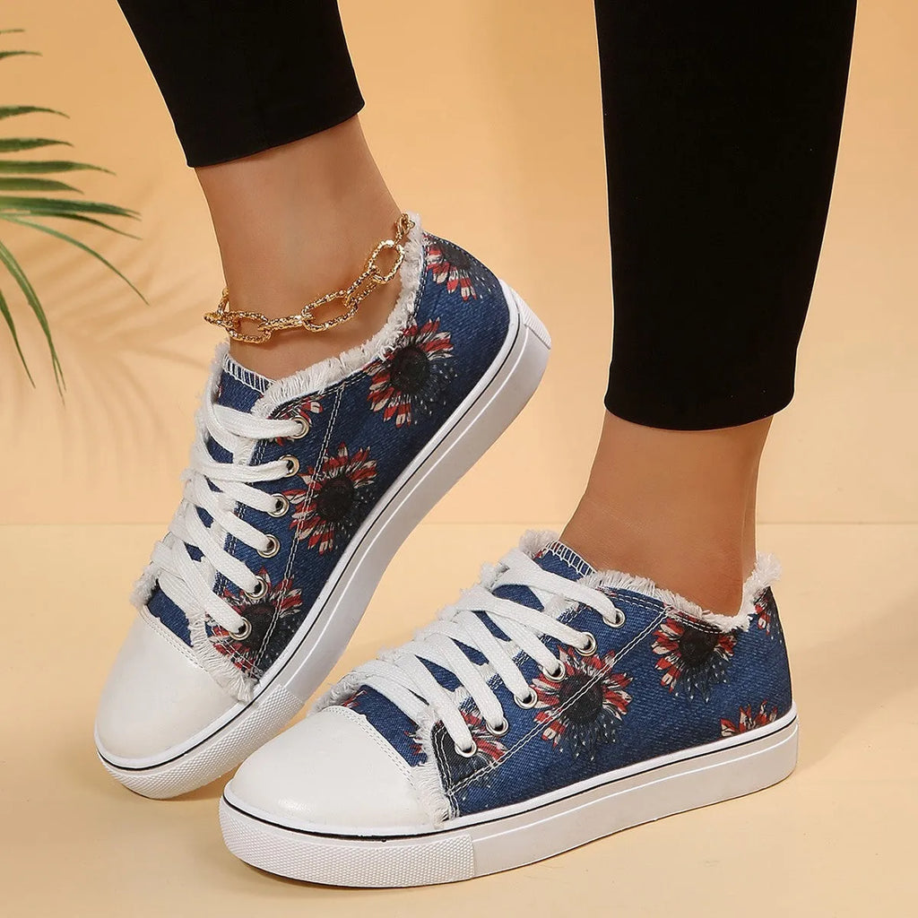 Women's flat canvas shoes with flower print, lace-up front, low-top design, and rubber sole in white green twig and denim colours.