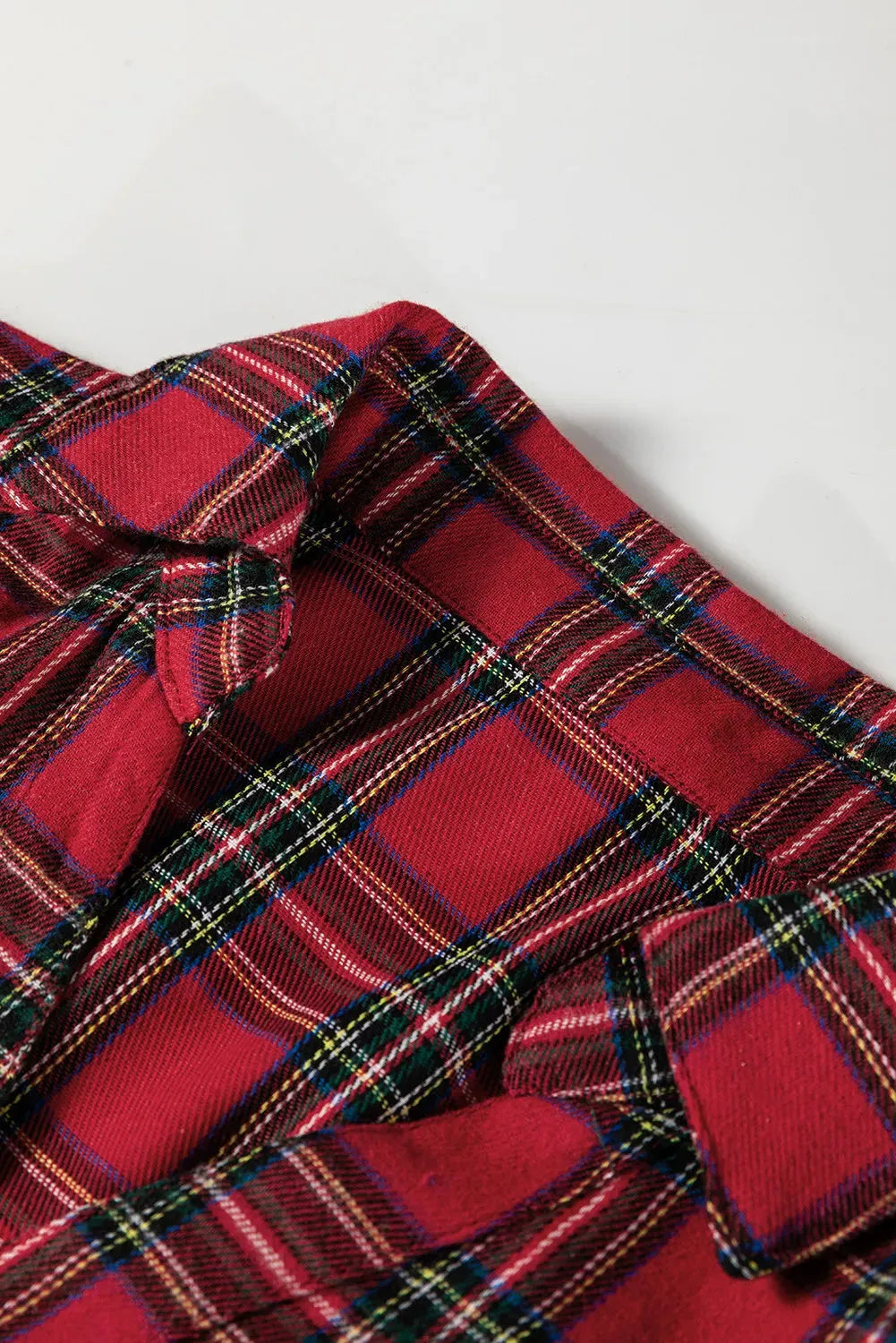 Red and black plaid mini dress with a shirt collar, half-button front, long sleeves, and a ruffle hem.