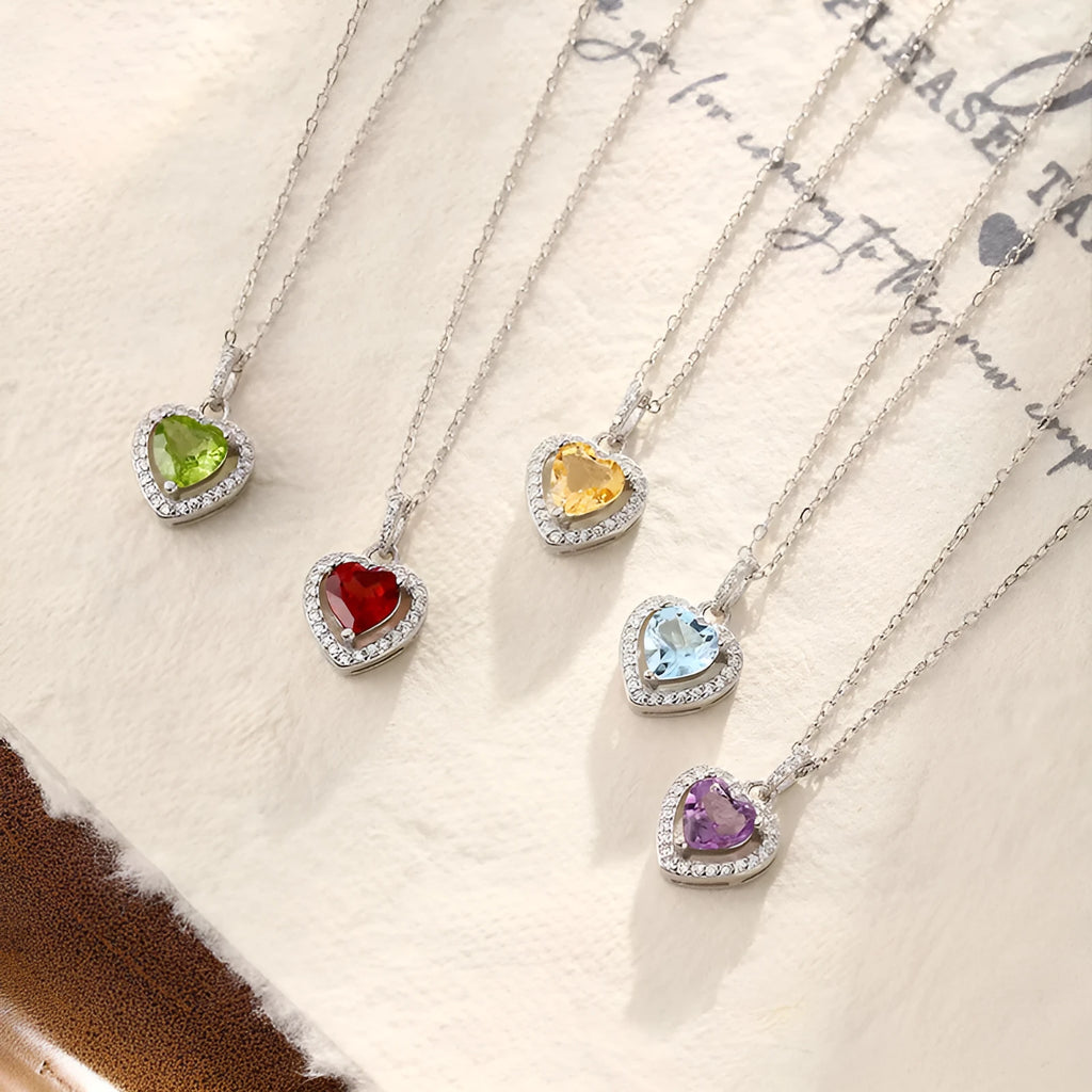 Heart-shaped sterling silver necklace with a coloured gemstone on an adjustable cross chain.