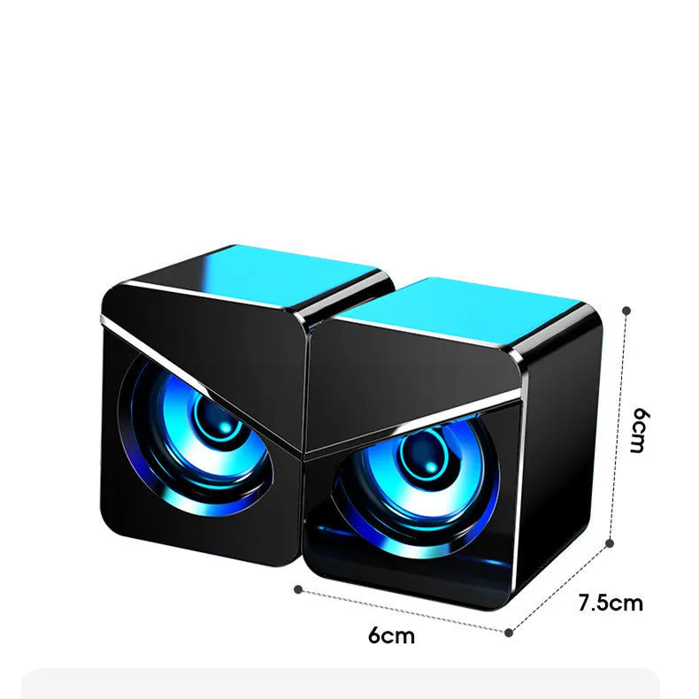 Black and white USB desktop mini speaker with cable next to a laptop computer.