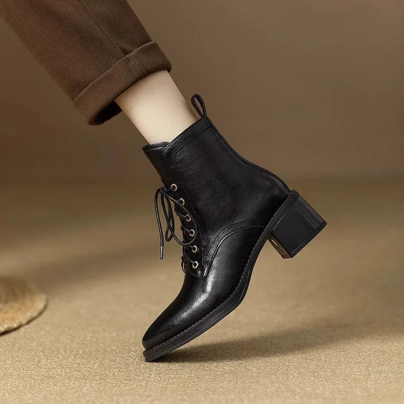 Women's black pointed-toe ankle boots with a short shaft and a low heel on a plain background.