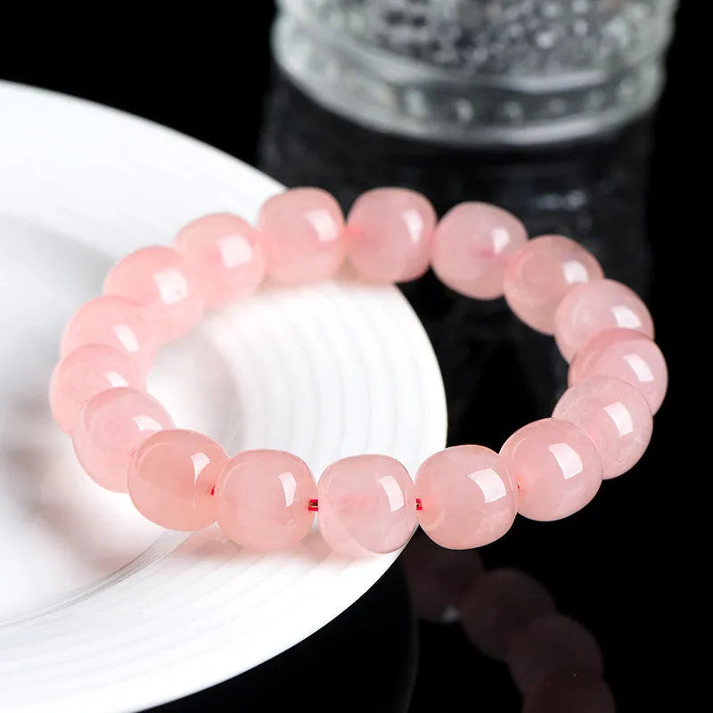 Natural pink crystal bracelet with 19 polished barrel-shaped beads on a wrist, showing geometric design.