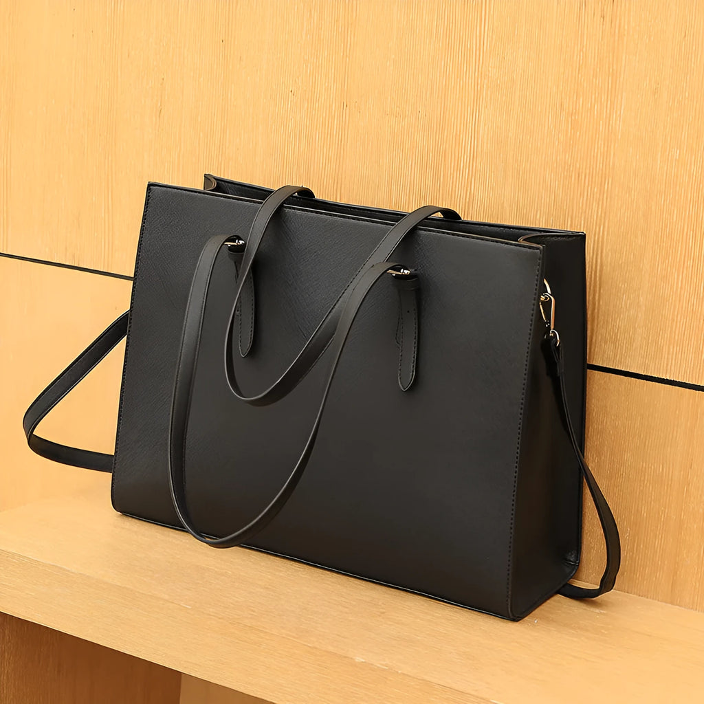 Black women's structured business computer bag showing front sandwich pocket and three adjustable shoulder straps.