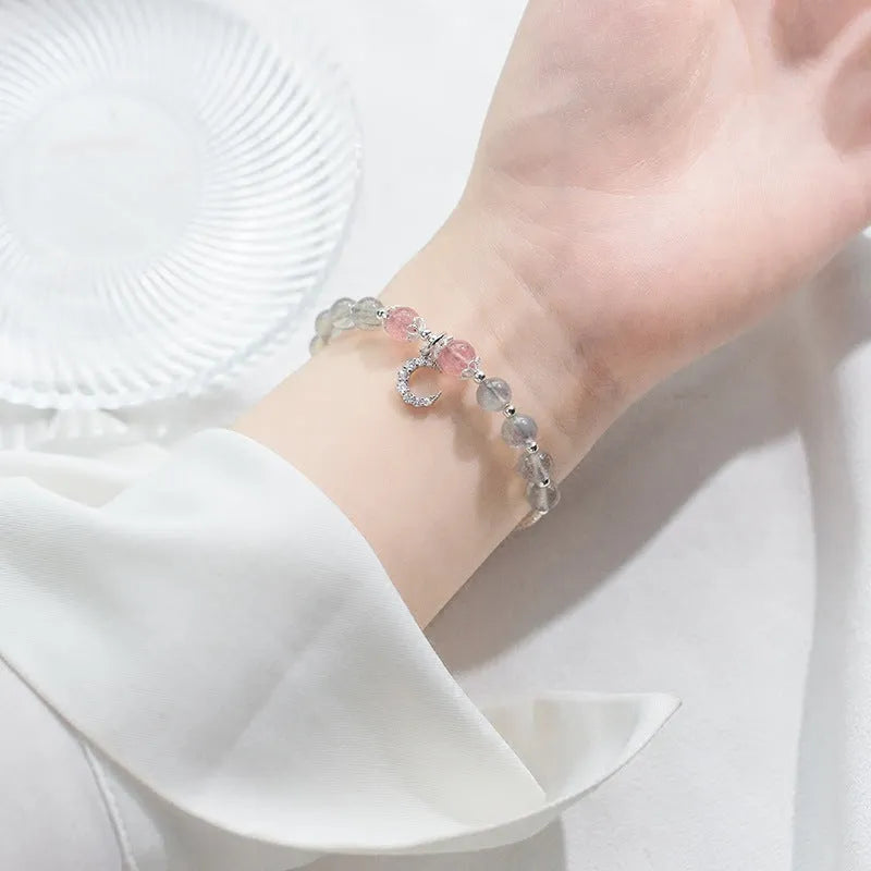 Handmade silver-tone adjustable bracelet with a moonstone bead and small crescent moon charm on a white background.