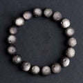 Natural obsidian crater ball bracelet with hand-ground texture, showing silver stone meteorite colour variation