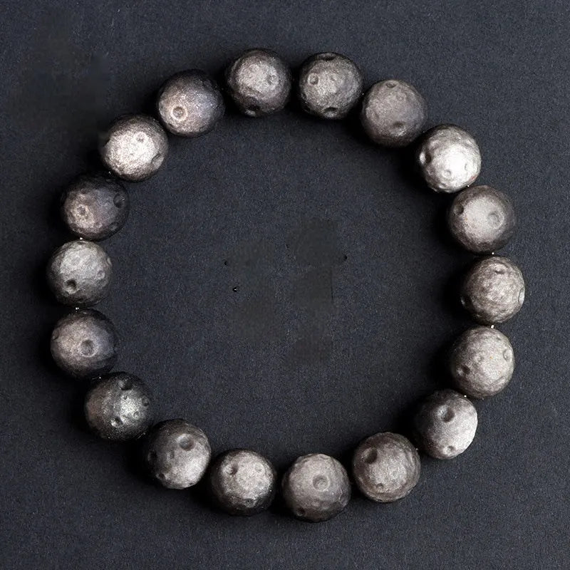 Natural obsidian crater ball bracelet with hand-ground texture, showing silver stone meteorite colour variation