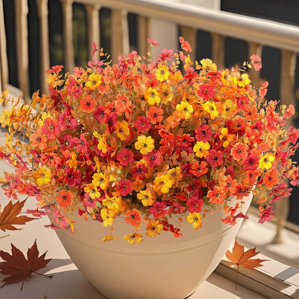Artificial flower bouquet in autumn colours of red, yellow, and orange for home and event decoration.