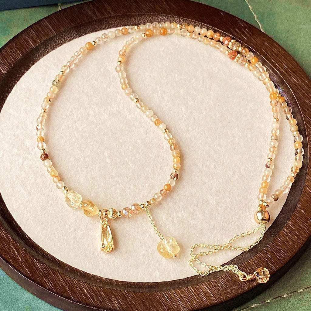 Gold three-circle layered bracelet with caramel citrine stones and a Saturn charm.