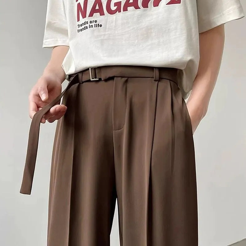 A woman wearing thin black wide-leg straight trousers with a loose, casual fit.