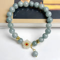 Handmade green jade bracelet with adjustable cotton cord fastening on a wrist.