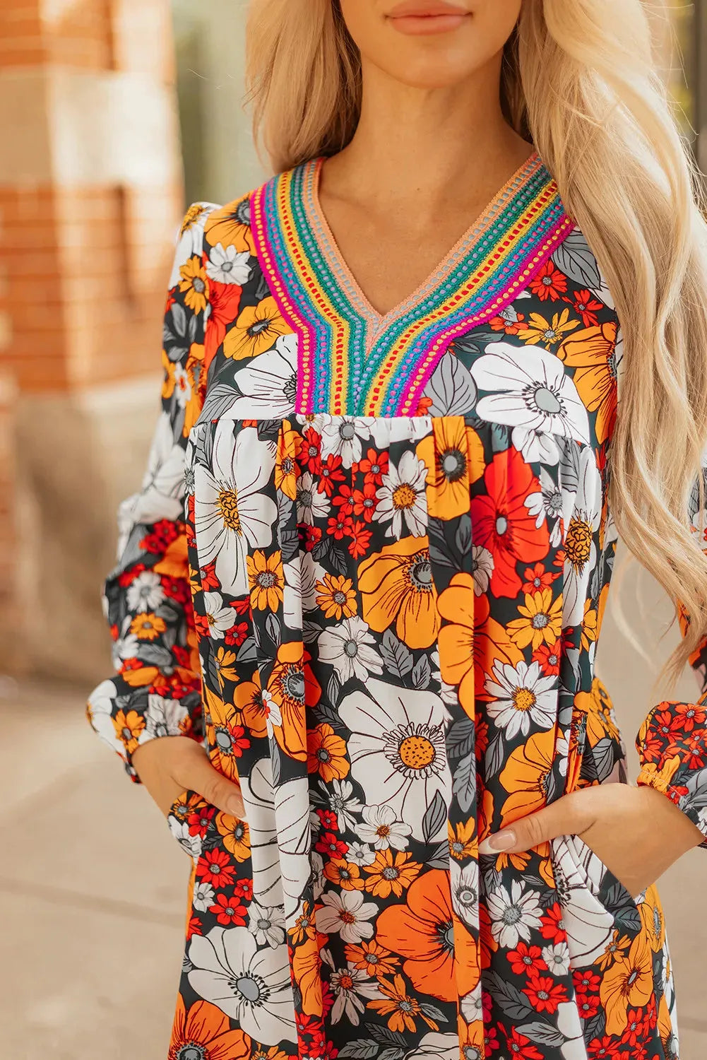 Orange floral and striped print long sleeve V-neck mini dress with lace detail on hanger.