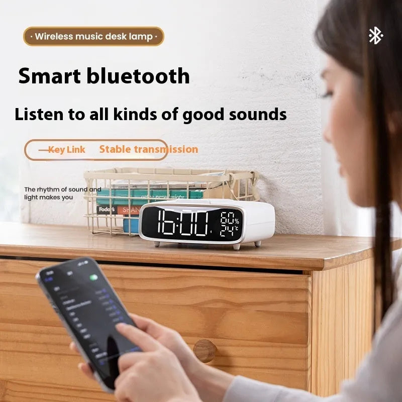 White Bluetooth speaker and wireless charging pad with integrated colour-changing night light on a bedside table.