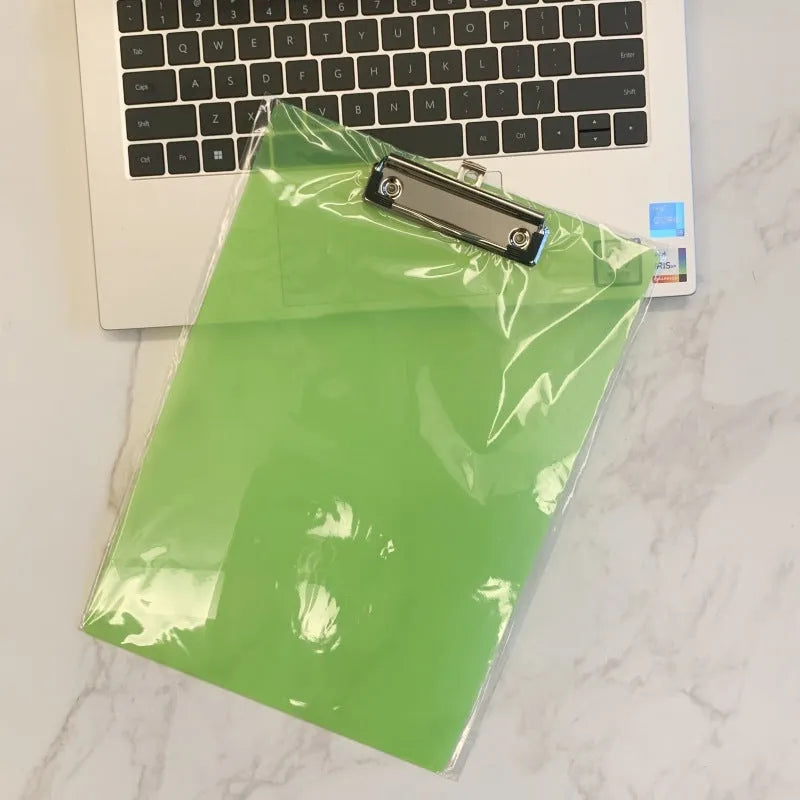 Clear A4 plate holder with metal clip and transparent writing pad in blue colour on a desk.