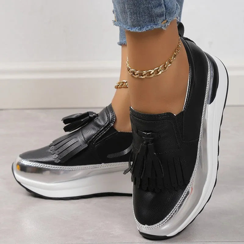 Women's black casual platform shoes with a tassel and muffin wedge heel on a white background.