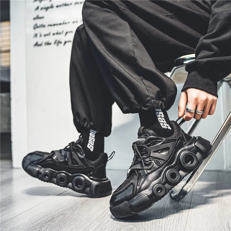 Men's black casual sneaker with thick rubber sole, mesh upper, abstract pattern, and lace-up front.