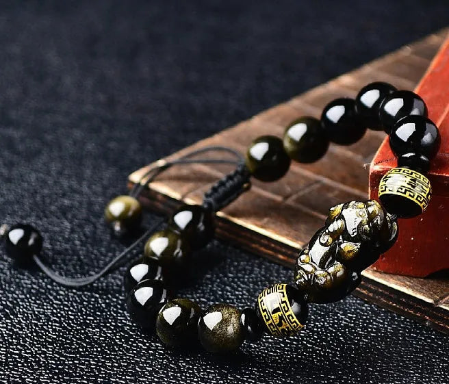 Hand-woven Golden Obsidian Pi Xiu bracelet with animal charm on wrist, showing bead detail.