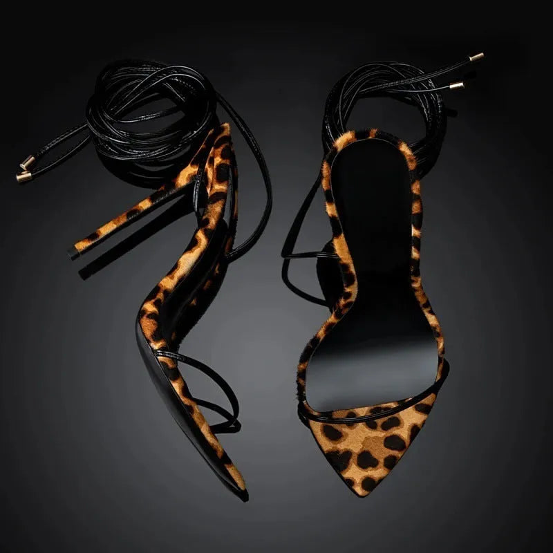 Women's leopard print sandals with a pointed toe and Roman lace-up buckle on a flat rubber sole.