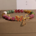 Close-up of a women's agate and tourmaline charm bracelet with butterfly and gourd shapes on a white background.