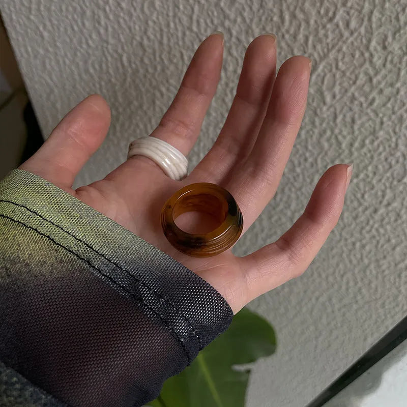 Geometric irregular resin wide ring in brown and white colour options on a hand.