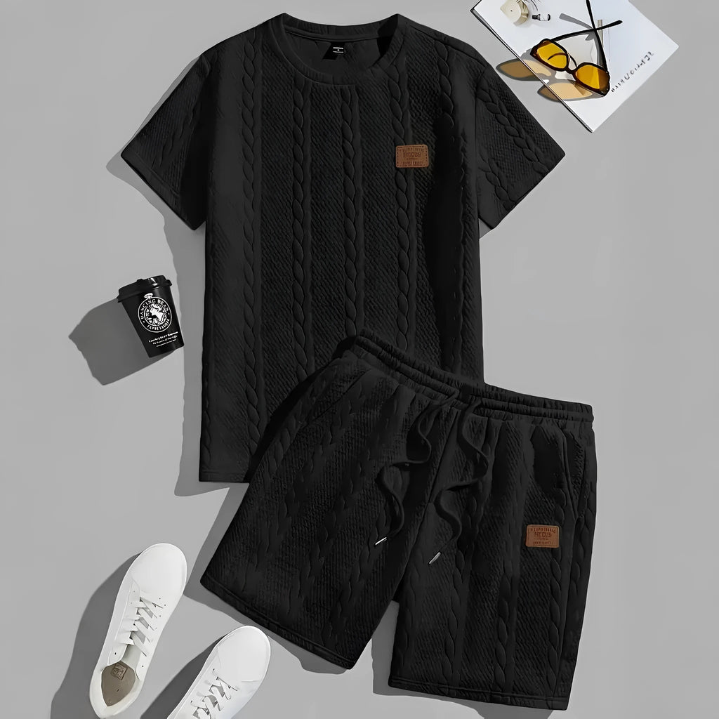 Men's black polyester sports two-piece set with rib short sleeves and a patch design detail.
