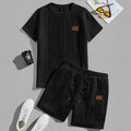 Men's black polyester sports two-piece set with rib short sleeves and a patch design detail.