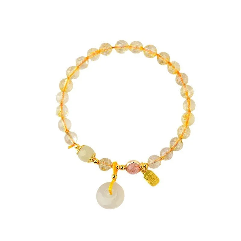 Gold rutilated quartz crystal bracelet with a safety buckle and a small rectangular blessing card pendant.