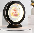 Pink magnetic levitation heart LED night light rotating above a triangular base on a desk.