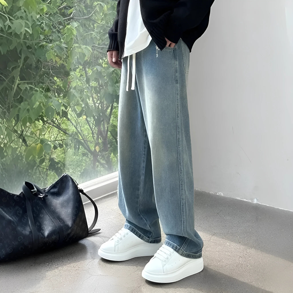 Men's straight-leg blue jeans with drawstring waist closure laid flat