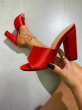 Women's satin surface sandals with chunky heel in black colour showing rubber sole and glossy finish