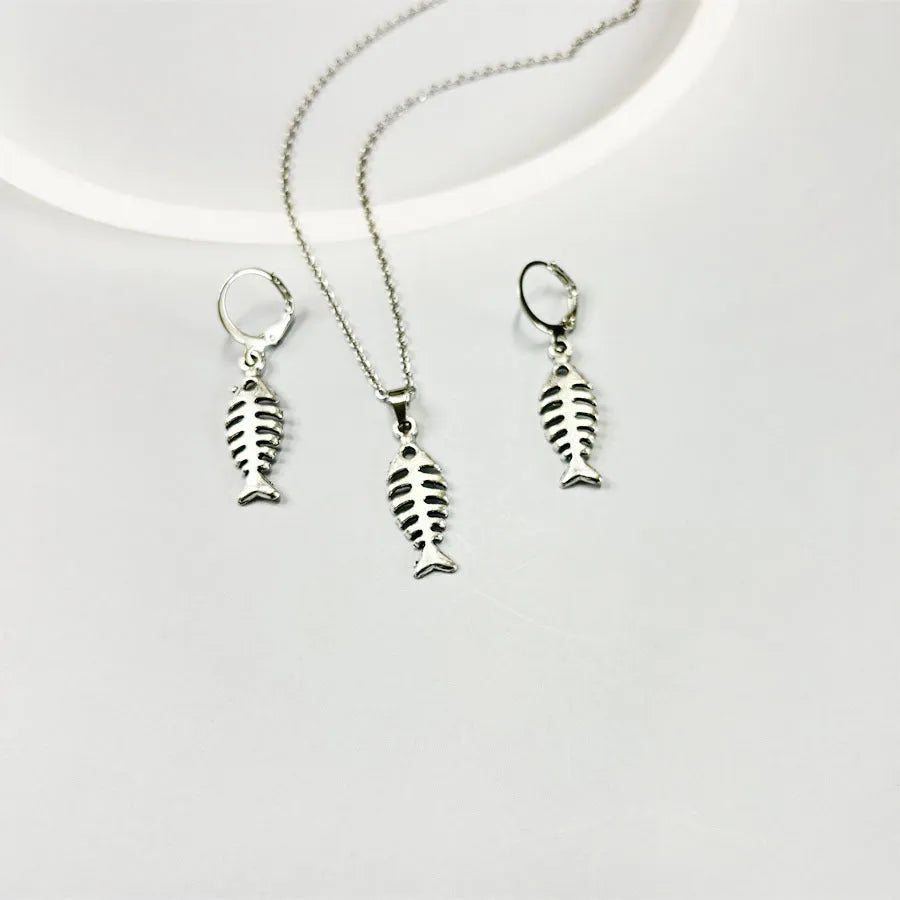 Fishbone pendant necklace with adjustable chain and matching retro earrings set on dark background