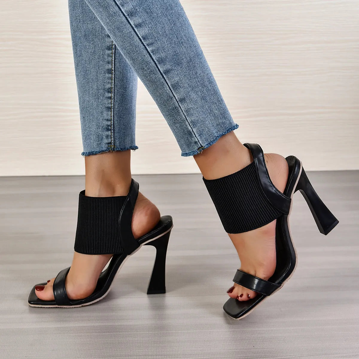 Women's black heeled sandals with elastic straps showing adjustable design