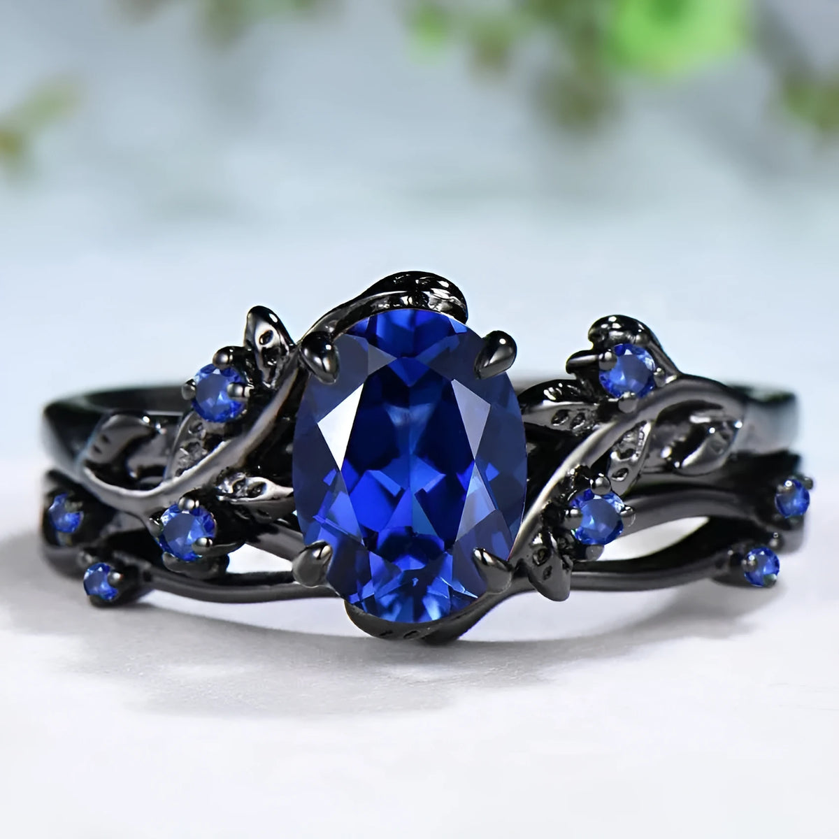 Gun black and navy blue rhinestone geometric couple ring for women on a plain background.