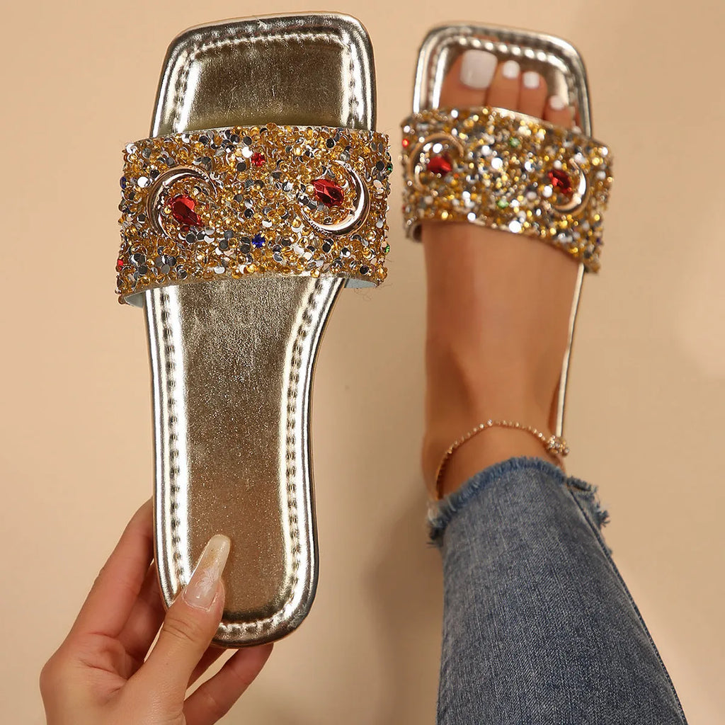 Gold women's flat slippers decorated with rhinestones and sequins on a PU upper with a rubber sole.