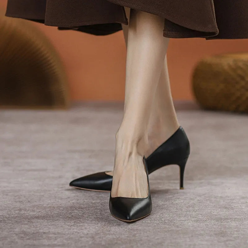 Black pointed-toe high heel shoes with a stiletto heel on a plain background