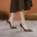 Black pointed-toe high heel shoes with a stiletto heel on a plain background