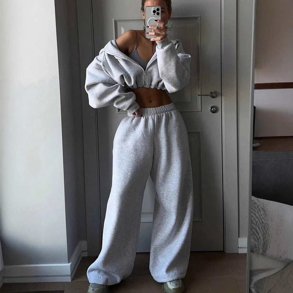 Man wearing a long sleeve sweater and matching trousers from a grey two-piece sports leisure suit set.