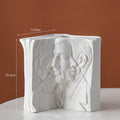 Ceramic book stand in lover design with glazed surface, approximately 15cm tall, on a wooden desk